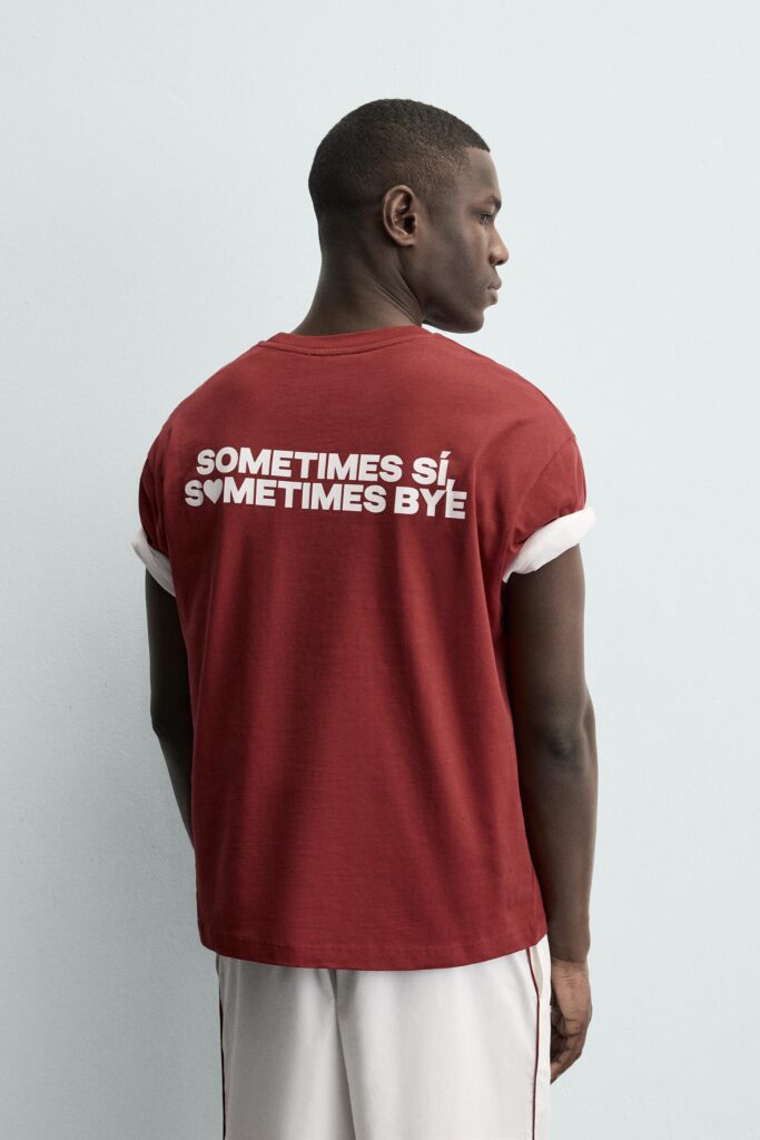 Red t-shirt featuring bold white typographic statement graphic on back placement.